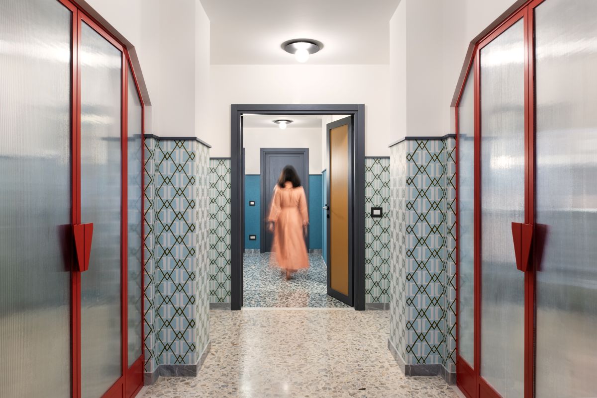 Moderná chodba s výraznými červenými sklenenými dverami a geometrickým obkladom v retro štýle.
