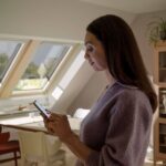 Žena s mobilom priestore so strešnými oknami Velux.