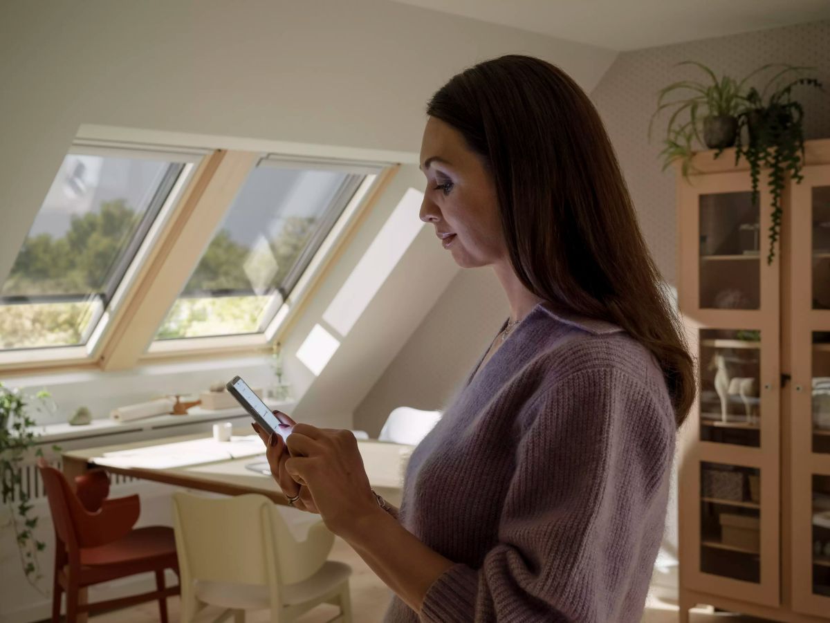Žena s mobilom priestore so strešnými oknami Velux.