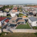 Panoramatický pohľad na modernú rezidenčnú štvrť s domami s rovnou strechou a trávnatými záhradami.