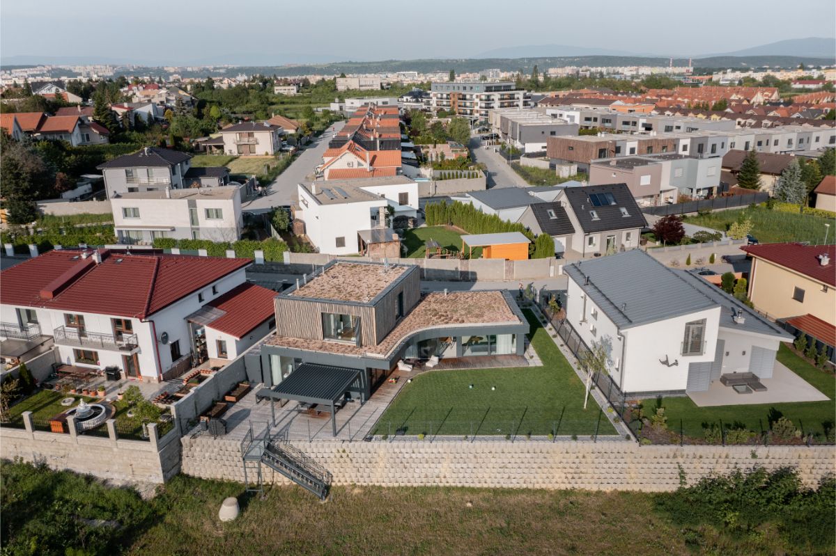 Panoramatický pohľad na modernú rezidenčnú štvrť s domami s rovnou strechou a trávnatými záhradami.