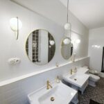 Biela moderná kúpeľňa s dvoma umývadlami a zrkadlami v štýle art deco.