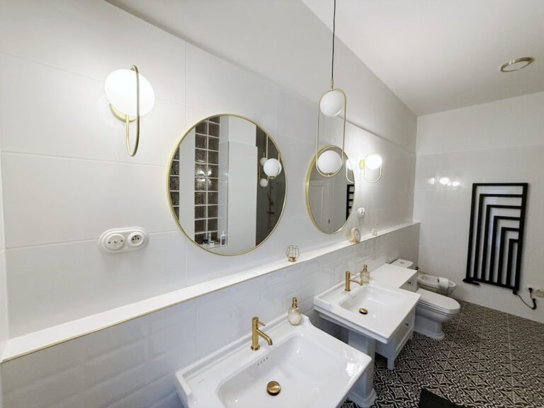 Biela moderná kúpeľňa s dvoma umývadlami a zrkadlami v štýle art deco.