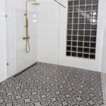 Bielo-čierna moderná kúpeľňa s walk-in sprchovým kútom a vzorovanými dlaždicami.