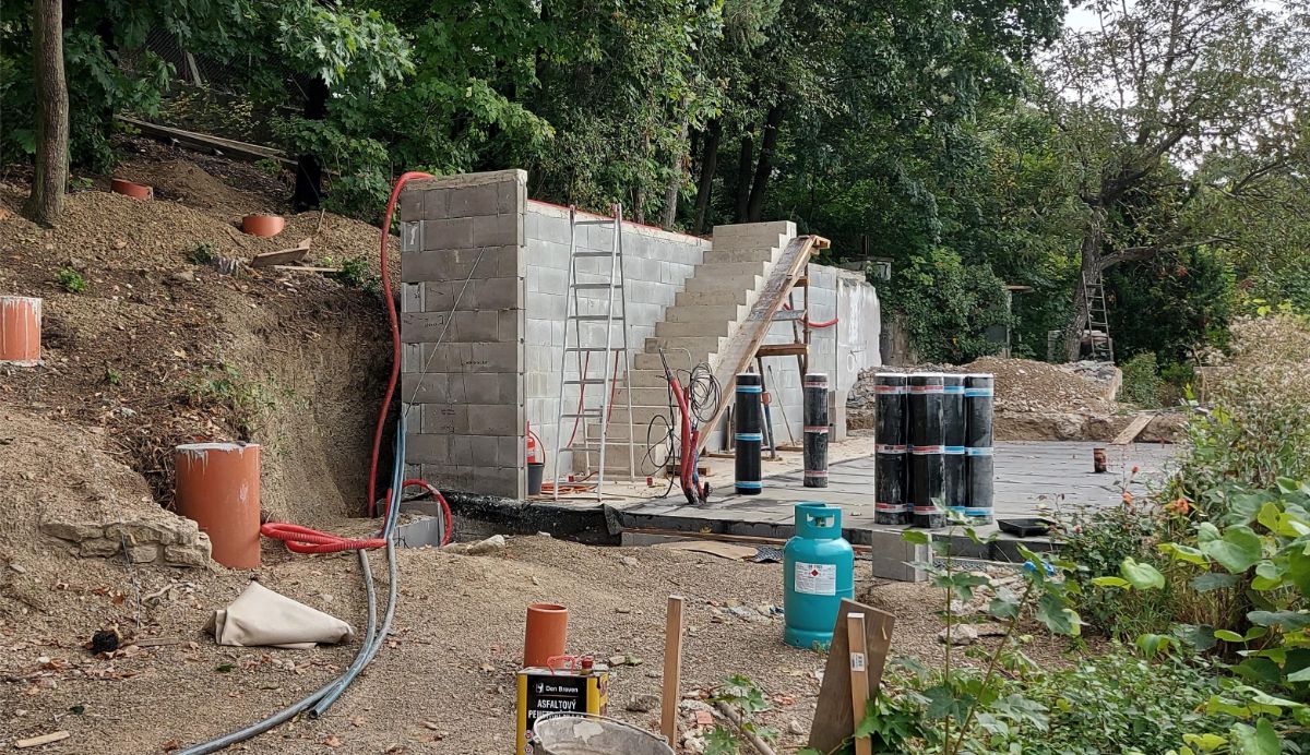 Proces výstavby. Betónový múr slúži ako opora pre polozapustené prízemie, ktoré v lete príjemne chladí. 