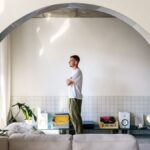 Architekt Alan Prekop vo vlastnom byte pri sedačke, obrátený smerom k oknu.