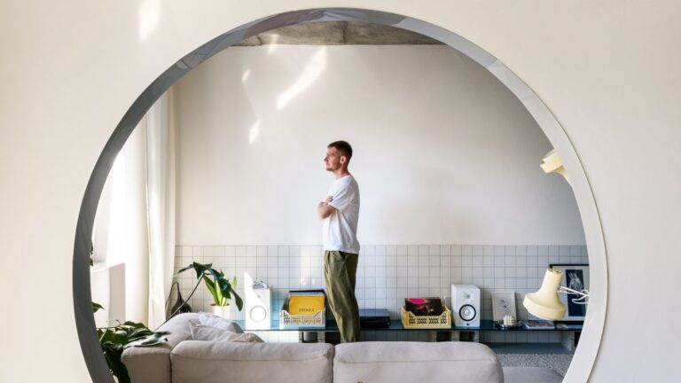 Architekt Alan Prekop vo vlastnom byte pri sedačke, obrátený smerom k oknu.