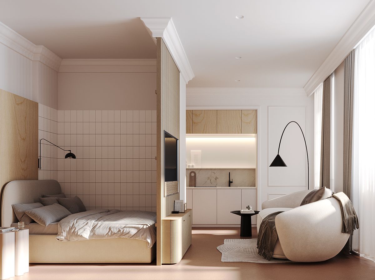 Interiér moderného apartmánu s posteľou, kuchynským kútom a oblou sedačkou.