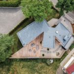 Pohľad z dronu na dom s veľkou špicatou terasou, sivou strerchou a upraveným dvorom.