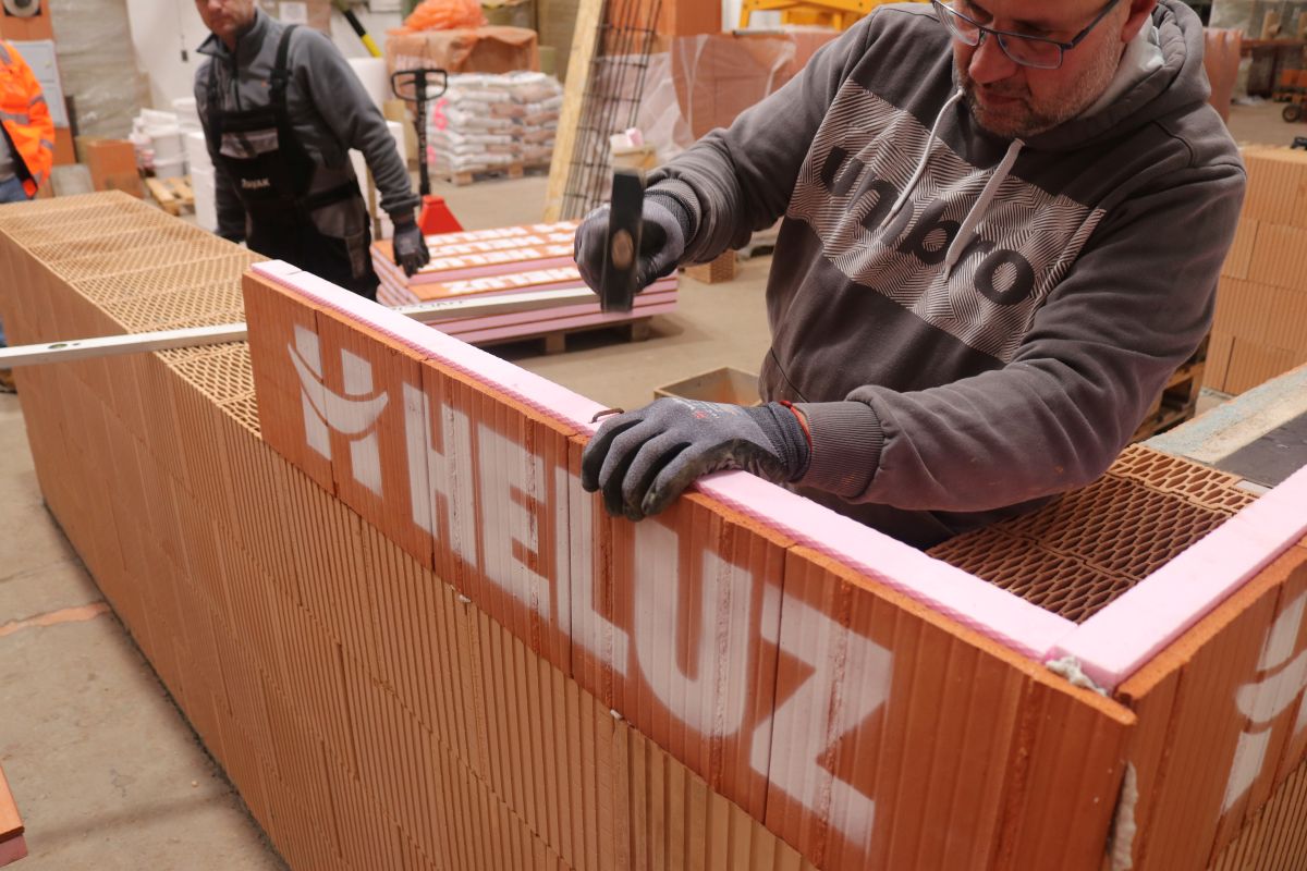 Muži pri stavaní hrubej stavby z tehál Heluz.