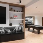 Herňa s biliardovým stolom, čiernym úložným priestorom s mramorovým obkladom a svetlou drevenou podlahou.