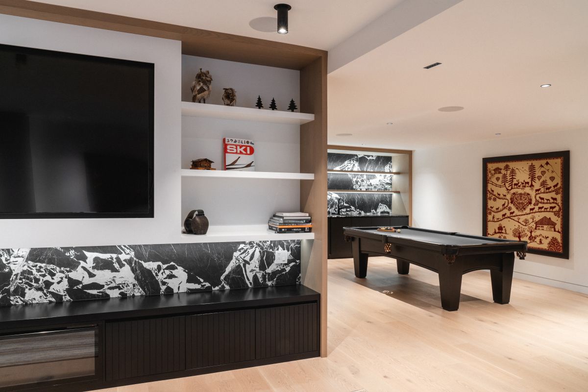 Herňa s biliardovým stolom, čiernym úložným priestorom s mramorovým obkladom a svetlou drevenou podlahou.