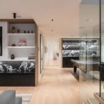 Časť herne s televízorom, policami a preskleným zábradlím oddeľujúcim miestnosť od chodby.