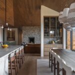 Otvorený priestor jedálne a kuchyne s mramorovým pultom, dreveným stropom a kamenným krbom.