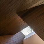 Drevený podhľad s lúčom svetla z atypického strešného okna.