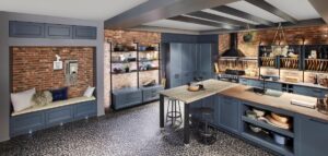 Moderná tmavomodrá kuchyňa v industriálnom štýle s tehlovou stenou, otvorenými regálmi a tmavou mozaikovou dlažbou.