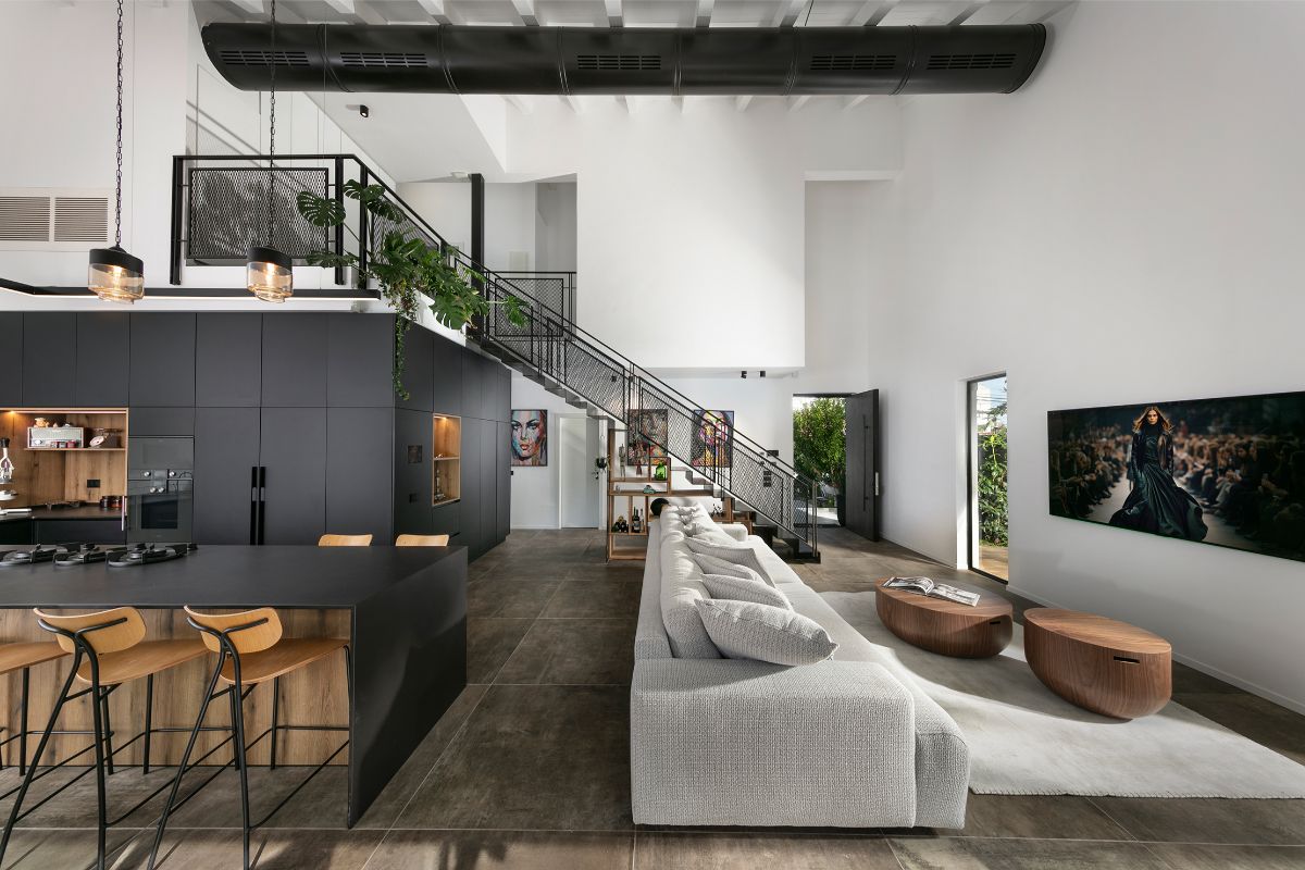 Interiér je oživený industriálnymi prvkami, ako je čierna rúra pod stropom či kovové zábradlie na galériu.