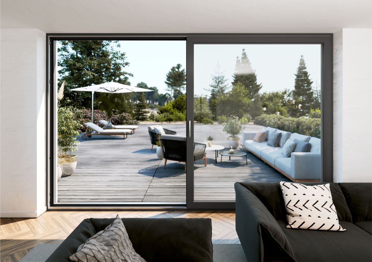 Moderná obývacia izba s čiernou sedačkou a veľkým posuvným oknom vedúcim na drevenú terasu.