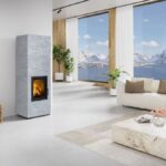 Akumulačné krbové kachle v interiéri s pohodlnou pohovkou a veľkoformátovými oknami s výhľadom na hory.