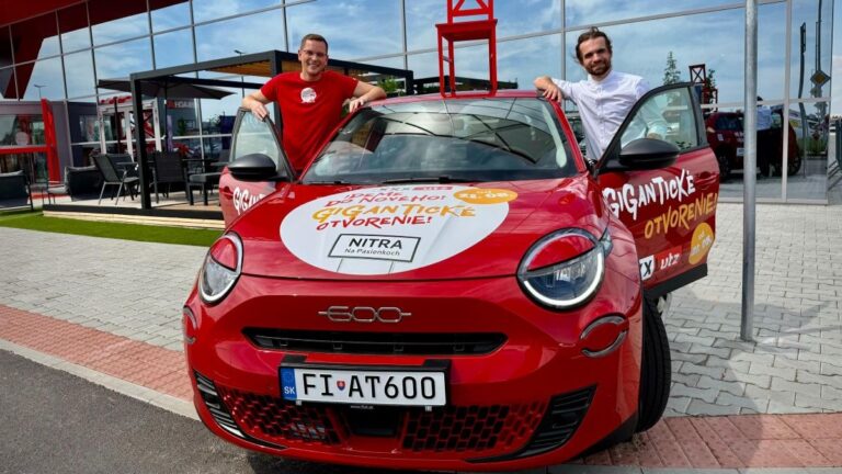 Mário Šmýkal a Michal Karcol pri aute s červenou stoličkou na streche pred predajňou XXXLutz