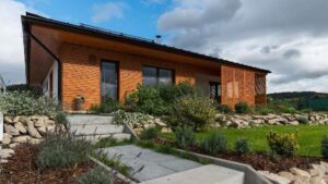 Montovaná drevostavba s chodníkom a upravenými záhonmi.