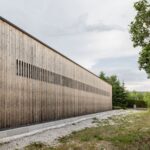 Pohľad zboku na átriový dom v Čachticiach s drevenou fasádou.