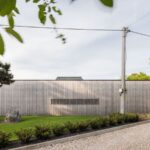 Átriový dom v Čachticiach s drevenou fasádou a upraveným trávnikom.