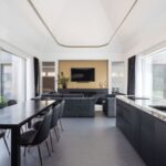 Interiér átriového domu v Čachticiach s vysokým klenutým stropom, tmavou kuchynskou linkou, jedálenským kútom aj sedacou súpravou.