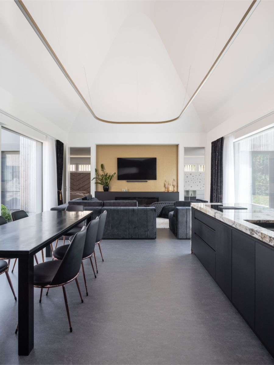 Interiér átriového domu v Čachticiach s vysokým klenutým stropom, tmavou kuchynskou linkou, jedálenským kútom aj sedacou súpravou.