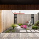 Pohľad do átria s chodníkom z dlažby a minimalistickými záhonmi.