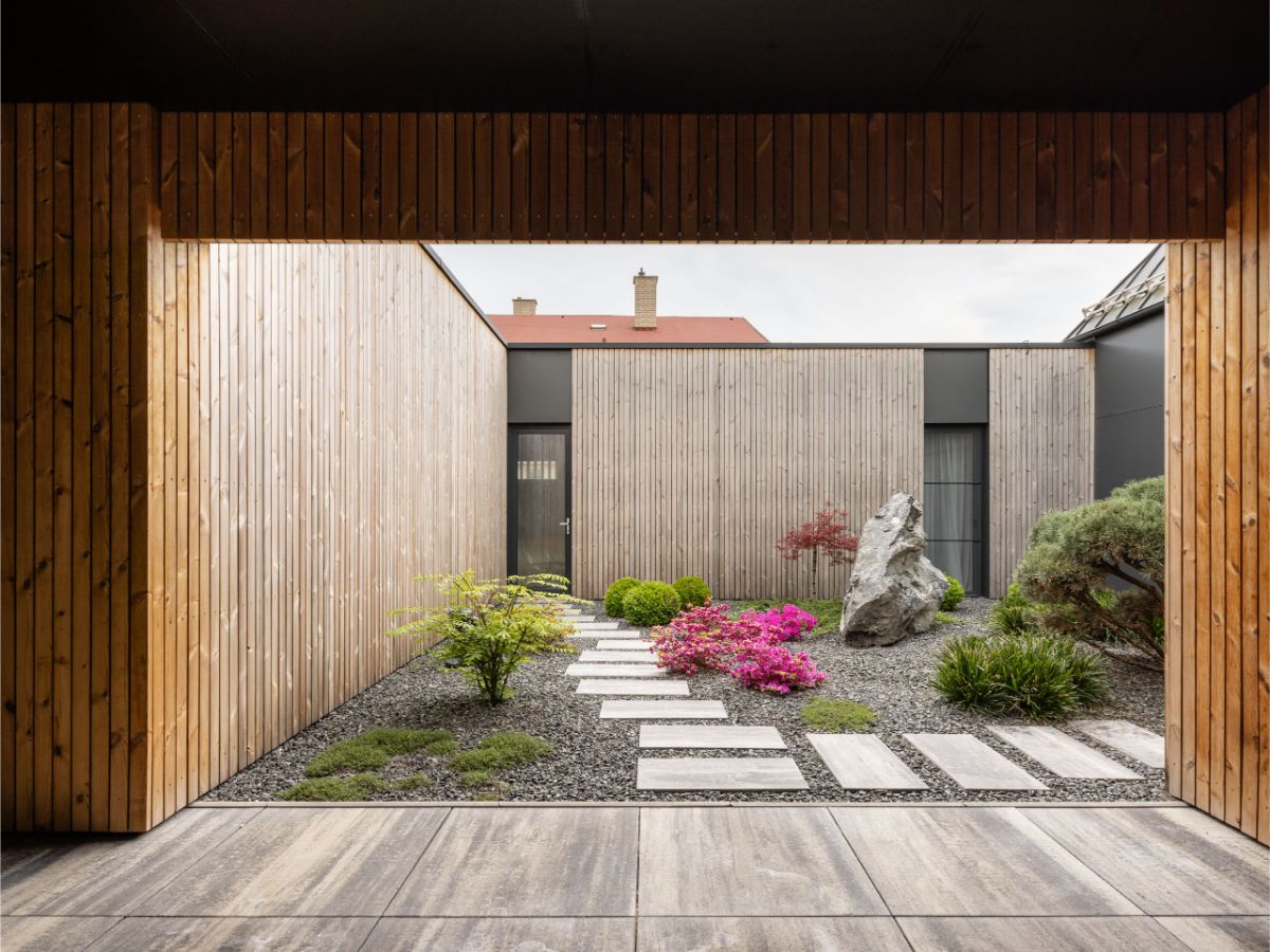 Pohľad do átria s chodníkom z dlažby a minimalistickými záhonmi.