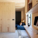 Drevený pracovný kútik s písacím stolom, stoličkou a vstavanými policami, s priechodom do izby.