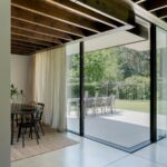 Jedáleň s čiernym okrúhlym stolom, stoličkami a jutovým kobercom s prístupom na terasu