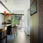 Kuchynský ostrovček s tmavou mramorovou doskou, drevenými barovými stoličkami a oranžovými lampami.