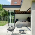 Vonkajšia terasa s dvomi čiernymi záhradnými kreslami a stolíkom pri dome.