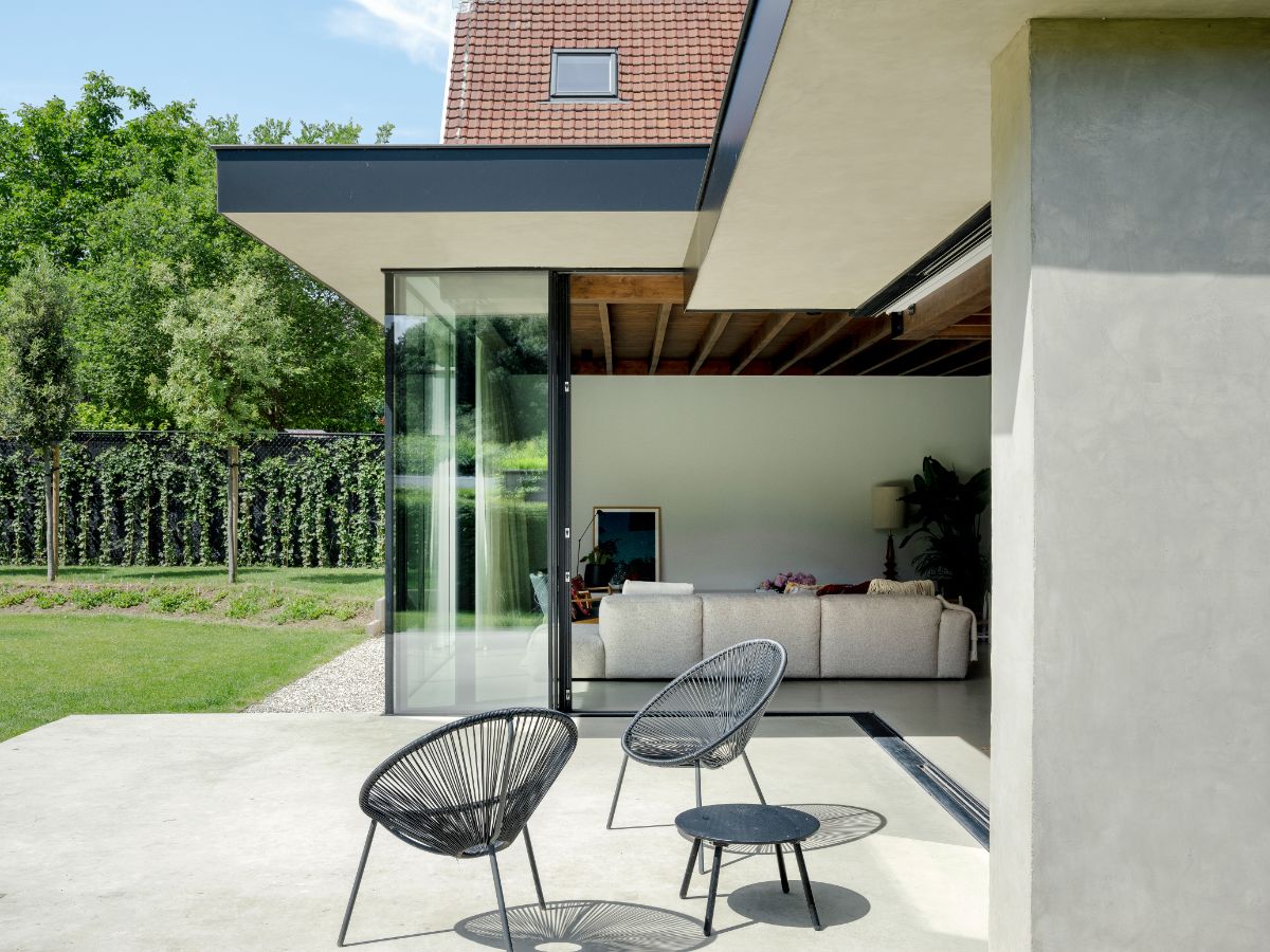 Vonkajšia terasa s dvomi čiernymi záhradnými kreslami a stolíkom pri dome.