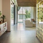 Chodba s terakotovým stropom, drevenou komodou a lesklou skriňou pred priechodom do obývačky.