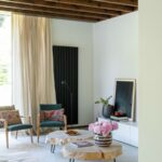 Dve tmavozelené kreslá s vankúšmi pri drevených stolíkoch s kovovými nohami.