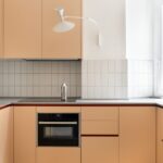 Moderná marhuľová kuchynská linka s čistými líniami, integrovanou rúrou a indukčnou varnou doskou.