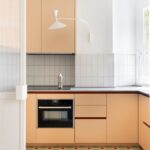 Moderná marhuľová kuchynská linka s čistými líniami, integrovanou rúrou a indukčnou varnou doskou.