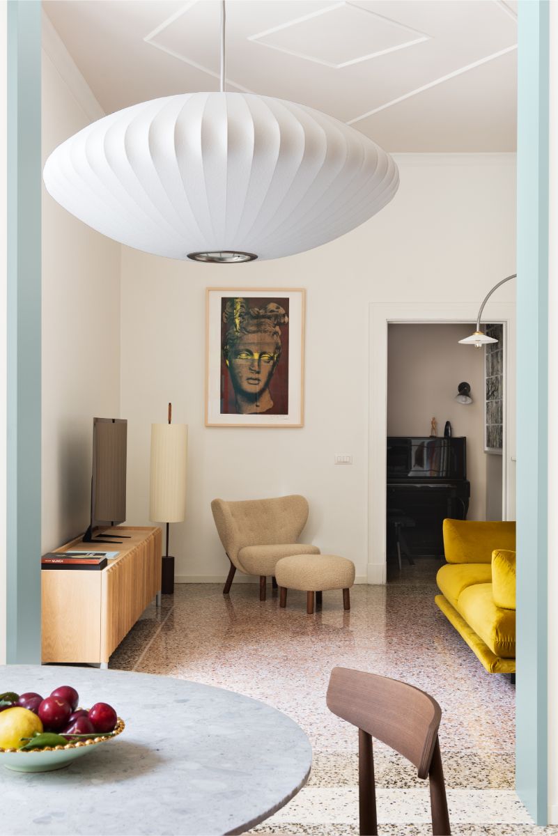 Obývacia izba s béžovým kreslom, drevenou skrinkou a žltou sedačkou.