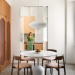 Žena stojí v priechode medzi jedálňou a kuchyňou s mramorovým stolom.