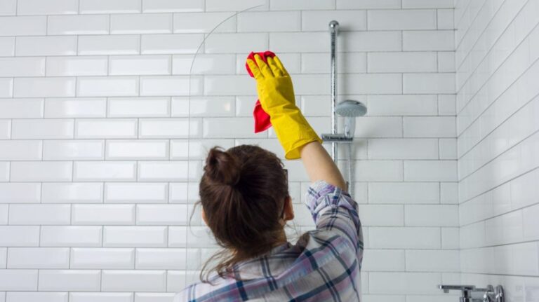 Žena pri čistení skla sprchového kúta.