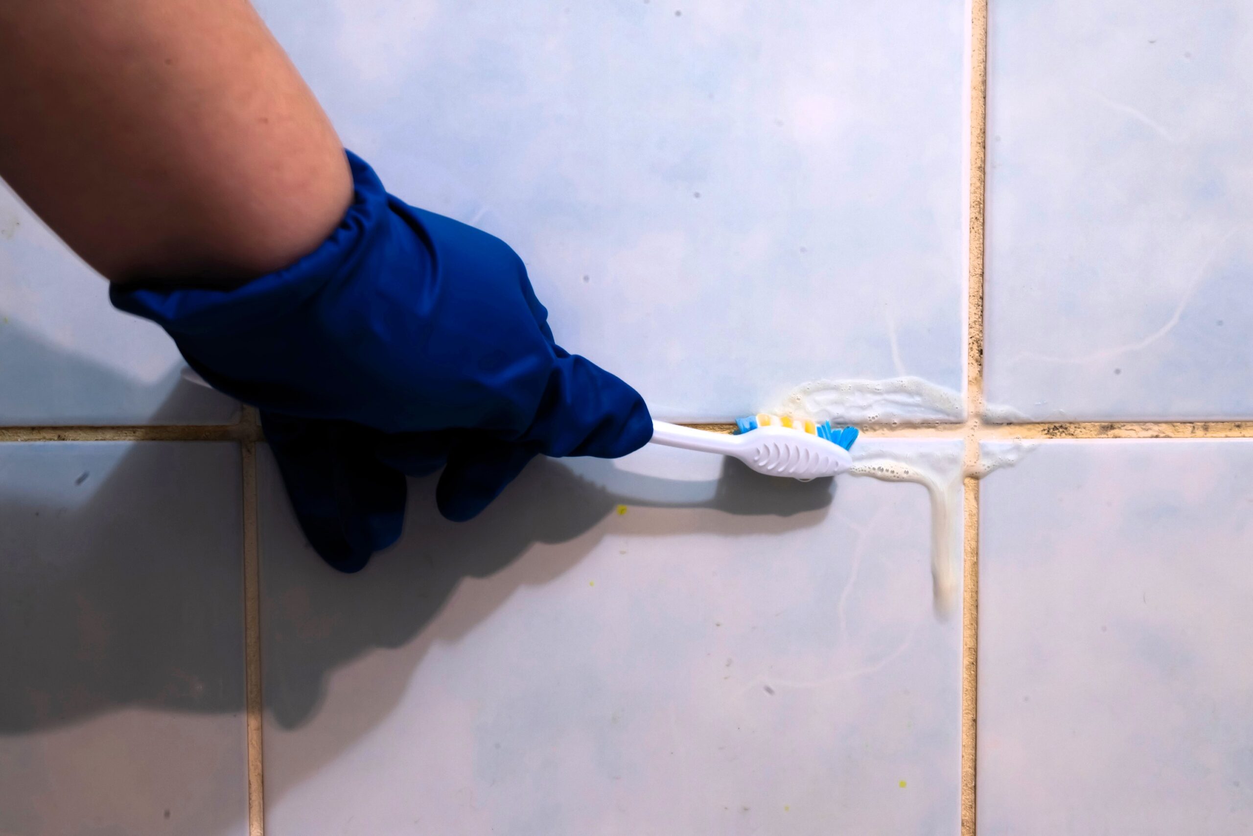 Detail na čistenie škáry medzi obkladačkami zubnou kefkou.