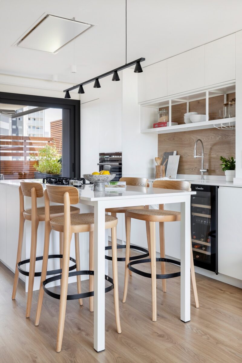 Minimalistické čierne osvetlenie nad stolom dodáva priestoru elegantný nádych, zatiaľ čo svetlé steny a drevená podlaha vytvárajú svetlú a príjemnú atmosféru.