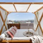 Terasa s drevenou hojdacou posteľou s baldachýnom s výhľadom na panorámu mesta.