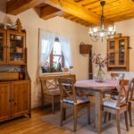 Jedáleň s dreveným stolom a stoličkami, masívnou drevenou komodou a dreveným trámovým stropom v rustikálnom štýle.