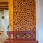 Masívna drevená stena tvorená kruhovými polienkami s tmavočervenou drevenou lavicou.