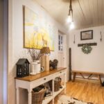 Vstupná hala s bielou konzolovou skrinkou, obrazom a kožušinovým kobercom na drevenej podlahe.