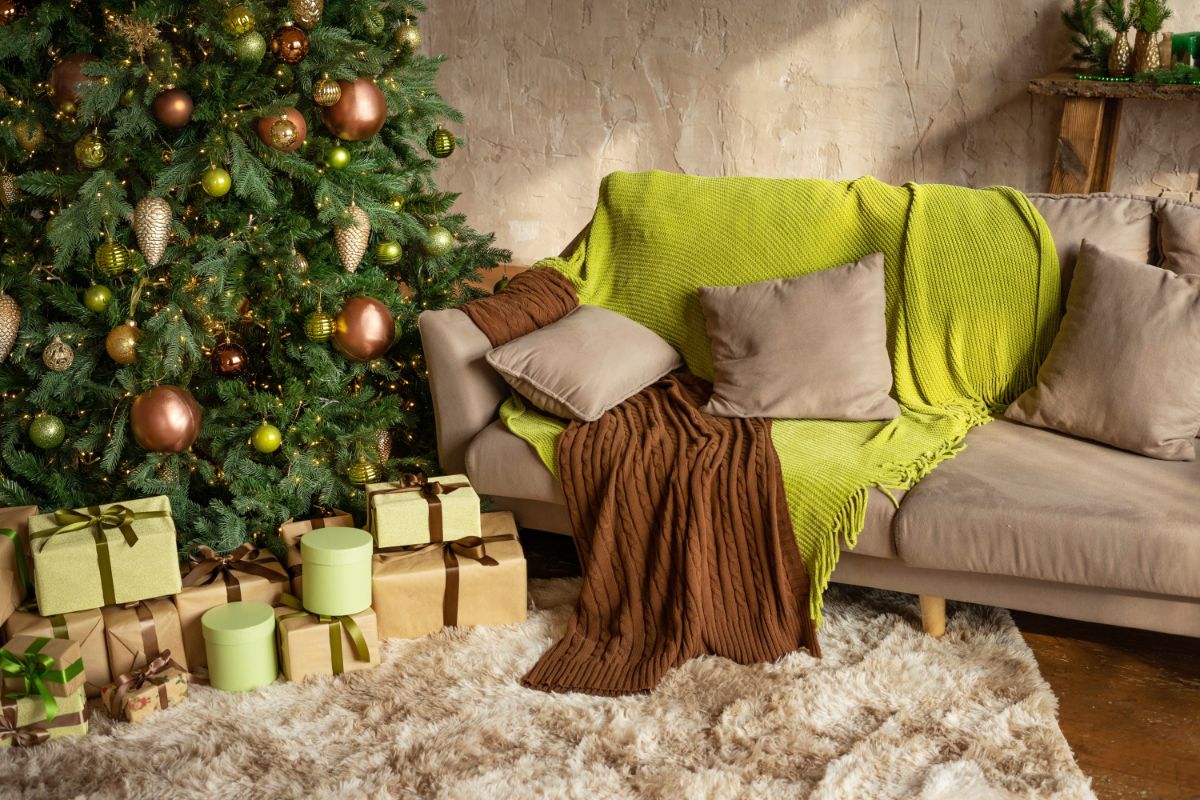Vianočná obývačka s ozdobeným stromčekom, huňatým kobercom a vankúšmi vo farbe Universal Khaki od Sherwin-Williams.